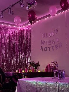 a room filled with tables covered in purple balloons and streamers hanging from the ceiling