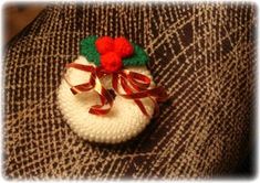 a knitted hat with a red flower and ribbon on the top is sitting on someone's lap