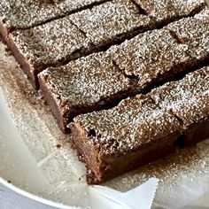 a plate that has some brownies on top of it with powdered sugar around the edges