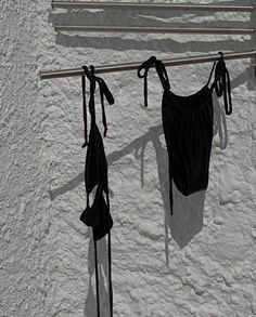 two black bras hanging from a clothes line on a white stucco wall with metal bars