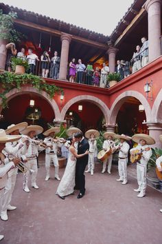 a group of people that are standing in front of a building with some hats on