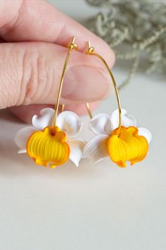 a pair of yellow and white flowers are being held by a person's hand