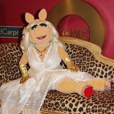 the miss piggy doll is sitting on a leopard print couch