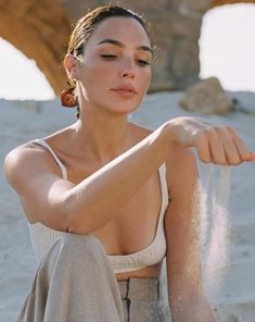 a woman sitting in the sand with her arm extended