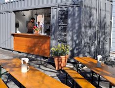 a man is standing in the back of a shipping container with wooden tables and benches