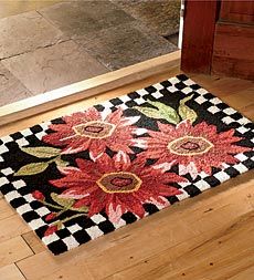 a black and white checkered floor with red flowers on the rug next to an open door