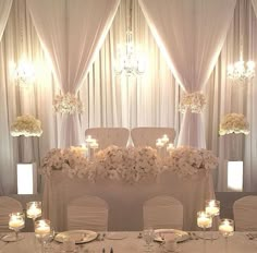 the table is set up with white flowers and candles for an elegant wedding reception or special event