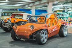 an orange car is parked in front of other cars