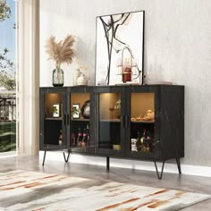 a black cabinet with glass doors and metal legs in front of a wall mounted art piece