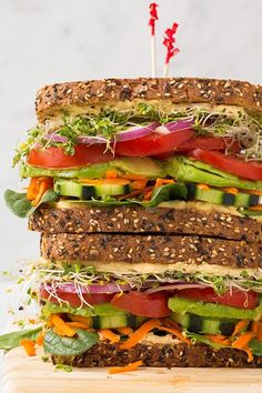 a large sandwich is stacked high with veggies and sprouts on it