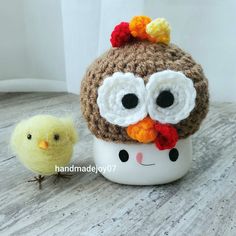 two small crocheted chickens sitting next to each other on a wooden table,