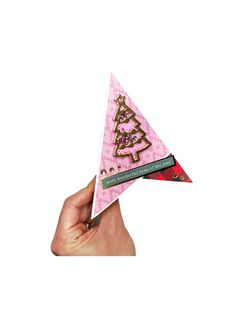 a hand holding up a pink and gold christmas tree ornament on it's side