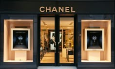 a chanel storefront with two mannequins in the window and lights on