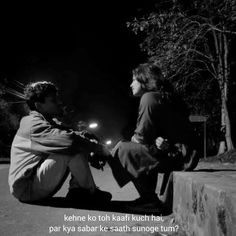 two people sitting on the ground at night with one person touching another's hand