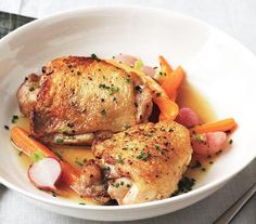 a roasted chicken on a plate with carrots and lemon slices