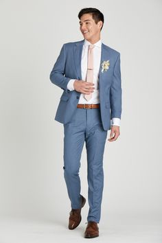 a man in a blue suit and pink tie is smiling at the camera while standing against a white background