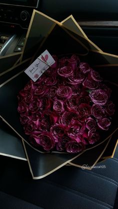 a bunch of flowers in a box on a car seat with a note attached to it