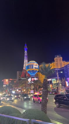 a city street filled with lots of traffic and tall buildings in the background at night