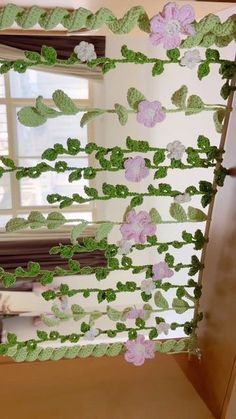 the window is decorated with green and pink paper flowers on it's trimmings