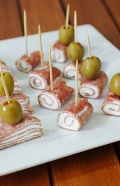 small appetizers are arranged on a plate with toothpicks and olives