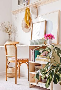 a room with a table, chair and bookshelf filled with plants in it