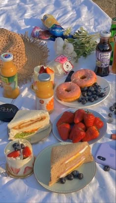 a table topped with sandwiches and fruit on top of a white cloth covered tablecloth