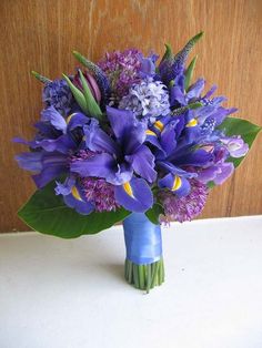 a bouquet of purple flowers sitting on top of a table