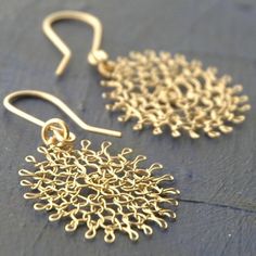 two pairs of gold - plated earrings with filigrees are on a table