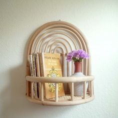 there is a shelf with books and a vase on it, next to a wall