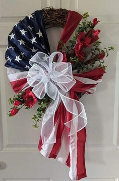 an american flag wreath hanging on a door with red, white and blue flowers in it