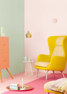 a pink and green room with two chairs, a dresser and a table in it