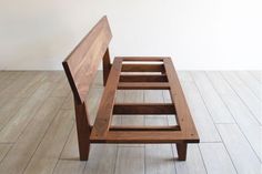 a wooden bench sitting on top of a hard wood floor next to a white wall