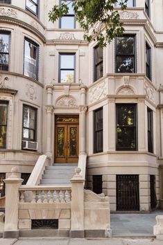 a large white building with stairs leading up to the front door and windows on each side