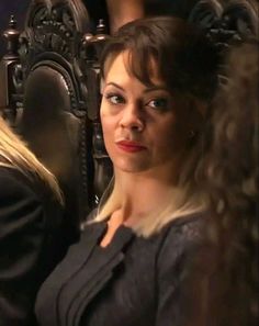 a woman sitting in a chair looking at the camera with an intense look on her face