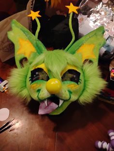 a green cat mask with yellow stars on it's head sitting on a table