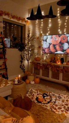 a living room decorated for halloween with pumpkins and decorations on the walls, lights strung from above