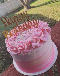 a birthday cake with pink frosting and gold letters