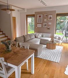 a living room filled with furniture next to a wooden table and white chairs on top of a hard wood floor