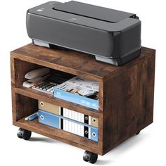 a printer is sitting on top of a small wooden shelf with books and binders