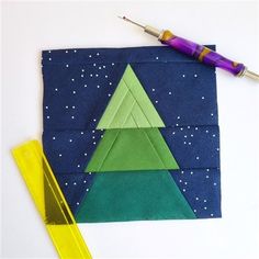 an origami christmas tree is on the table next to some markers and scissors