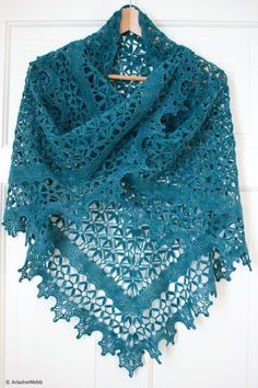 a blue crocheted shawl hanging on a door