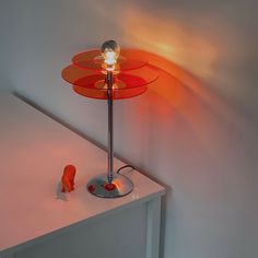 a lamp that is sitting on top of a white table next to a toy elephant