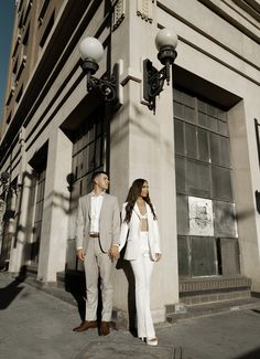 a man and woman standing in front of a tall building