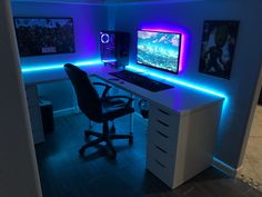 a computer desk with two monitors on it and blue lights in the room behind it