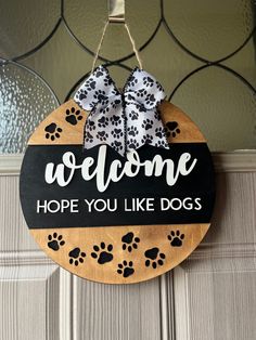 a welcome sign hanging from the front door with paw prints on it and a bow