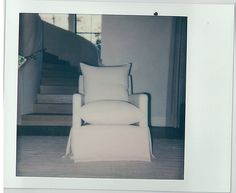 a white chair sitting in front of a stair case with pillows on top of it