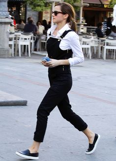 a woman walking down the street in black overalls