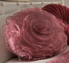 two pink flowers are on the back of a white bed with red ruffled pillows