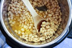 the beans are being cooked in the pot with a wooden spoon and is ready to be cooked