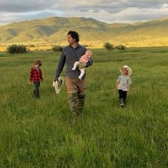 a man walking with two children in a field